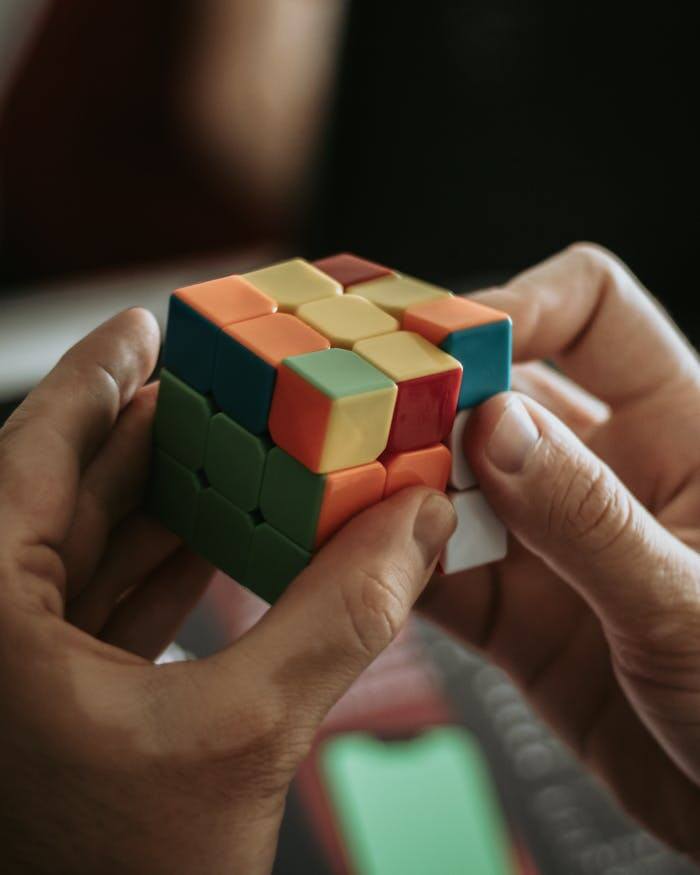 Close-up of hands solving a colorful Rubik's cube indoors.