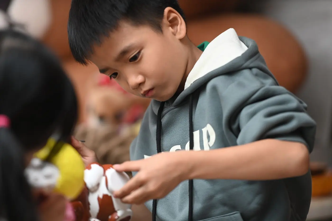 Focused young boy playing with a toy, showcasing concentration and leisure indoors.