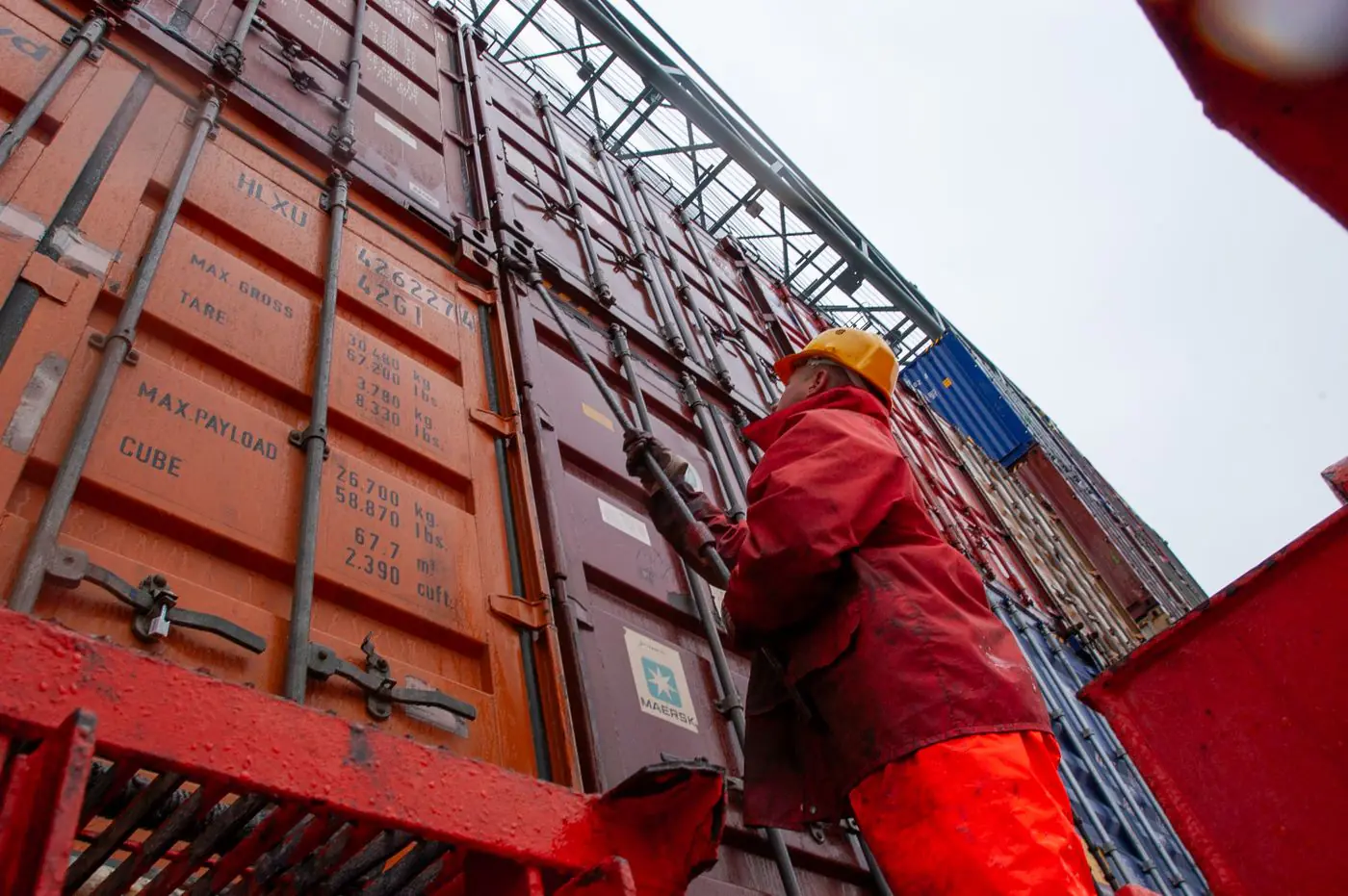 Industrial worker securing cargo containers on a rainy day at a shipping port. - King Squishy