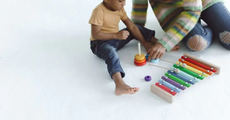 A mother and child enjoying playtime with a colorful xylophone on a white background. - King Squishy