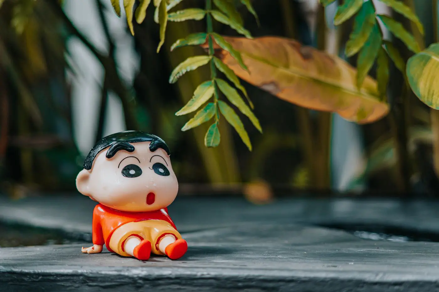豊かな緑の葉に囲まれた屋外に置かれたカラフルなカートゥーンキャラクタートイ - King Squishy