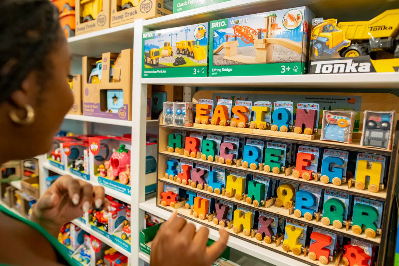 Woman explores colorful educational toys and alphabet blocks in a bustling toy store. - King Squishy