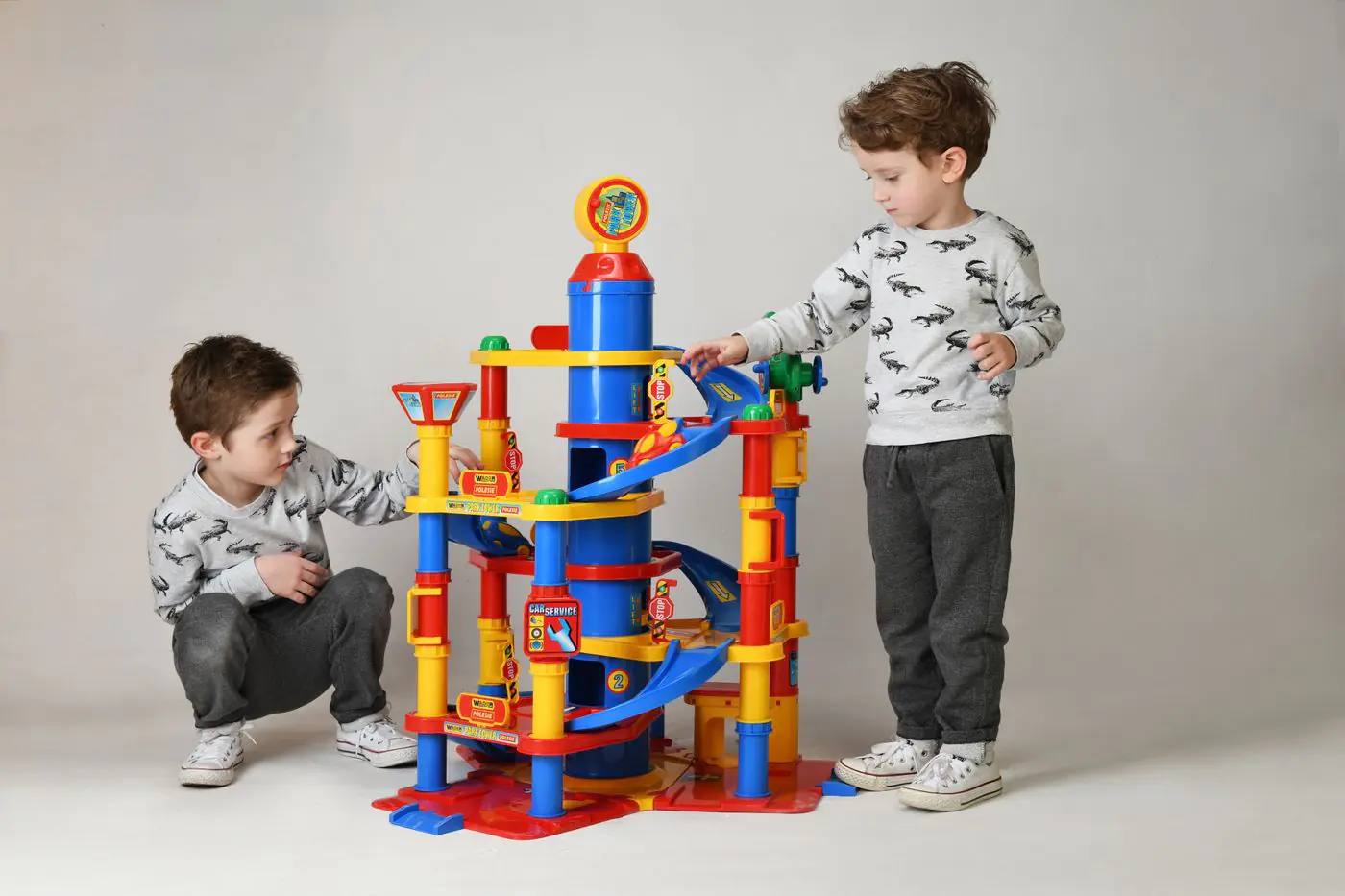Two boys engaging with a vibrant toy tower in a studio setting, showcasing playful childhood moments. - King Squishy