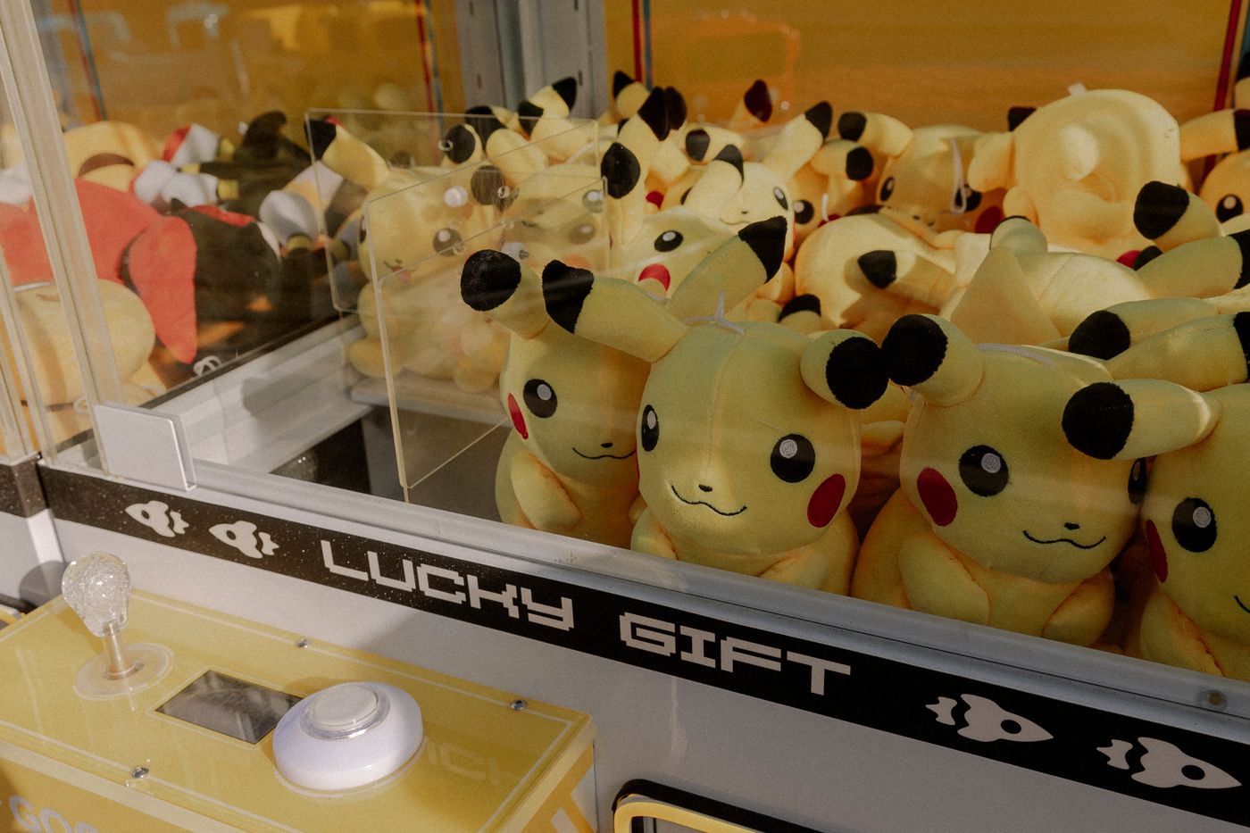 Pikachu-Plüschtiere in einem Greifautomaten mit der Aufschrift 'Lucky Gift'. - King Squishy