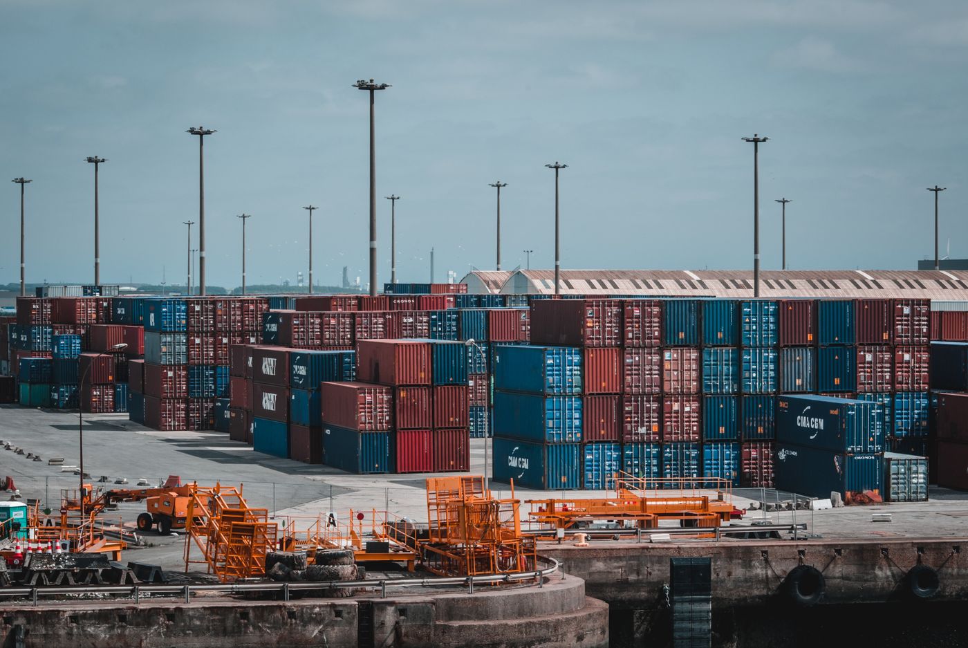 Bunte Frachtcontainer gestapelt in einem geschäftigen Industriehafen, die den globalen Handel zeigen.