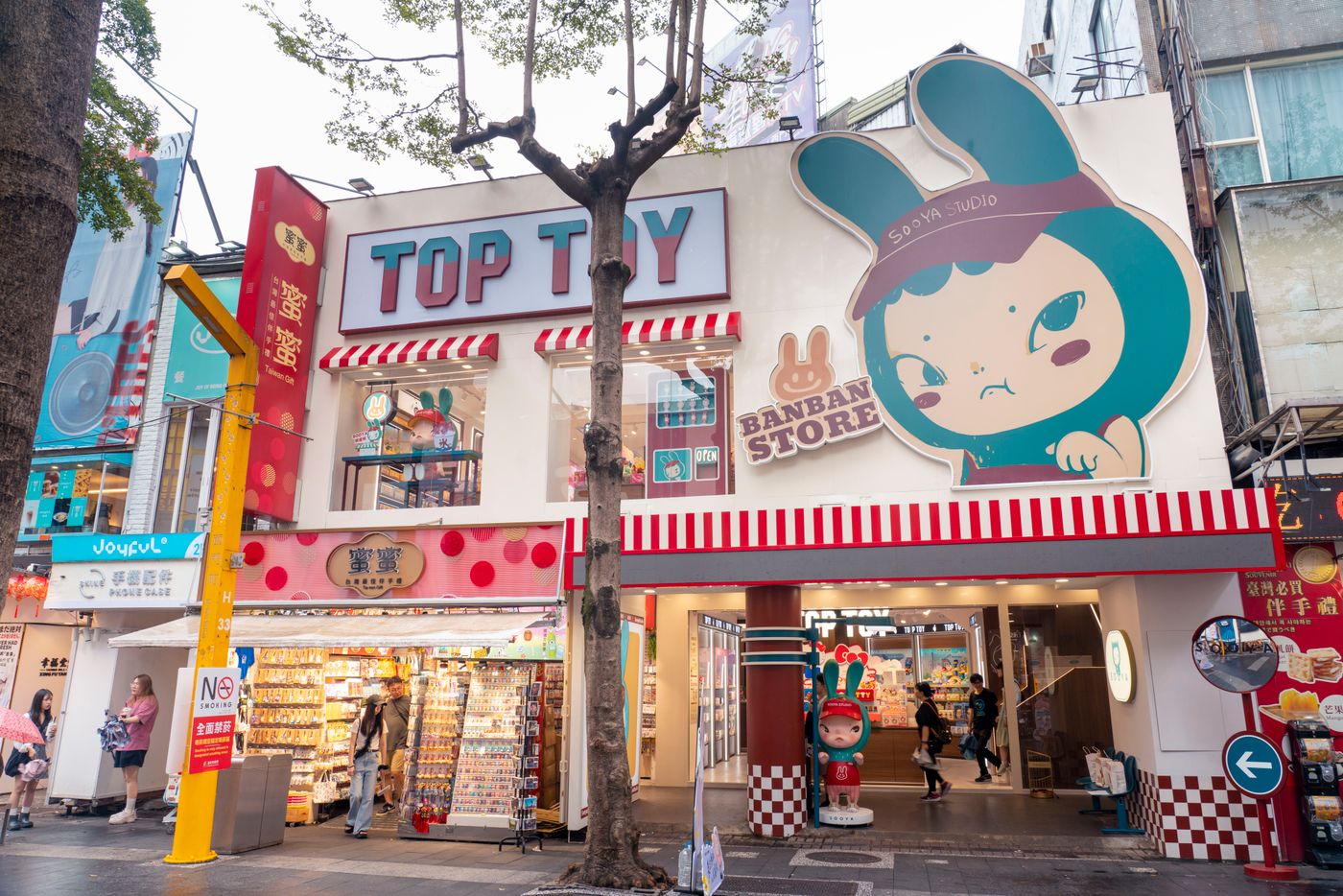 Bunte Spielzeugladen-Fassade mit großer Beschilderung und Grafiken in belebter städtischer Einkaufsgegend. - King Squishy