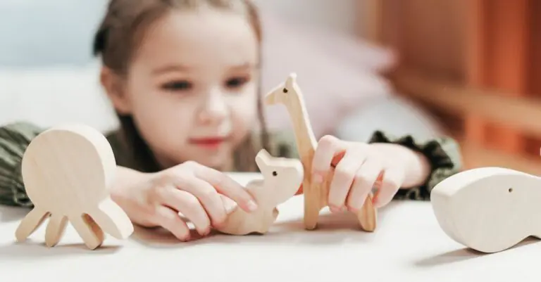 Young girl engages creatively with wooden animal toys in a playroom setting. - King Squishy