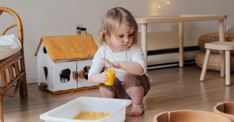 A young child playing with macaroni in a cozy indoor playroom setting. - King Squishy
