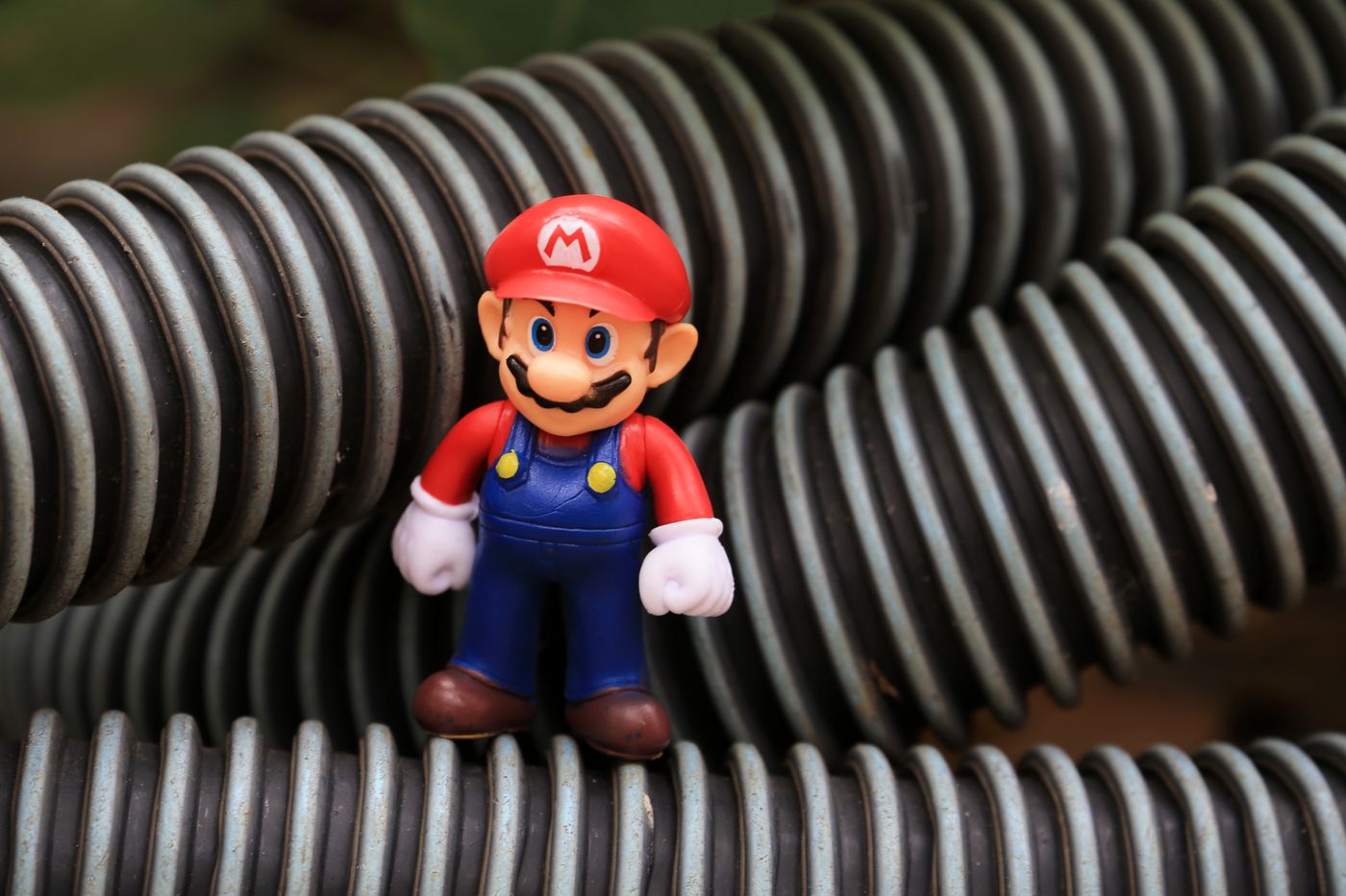 لقطة قريبة لمجسم لعبة Super Mario واقف بين أنابيب بلاستيكية ملفوفة.