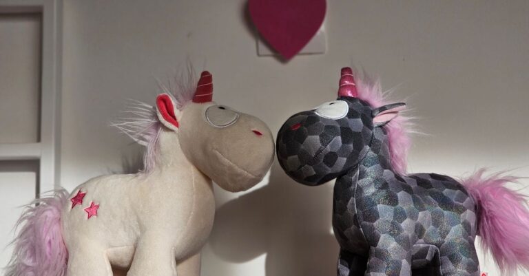 Two plush unicorn toys with pink manes and horns in a cozy indoor setting, perfect for a child' - Ki - King Squishy