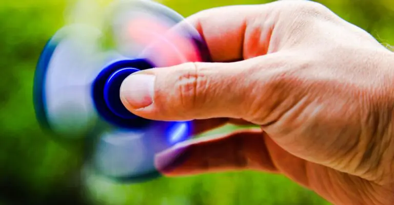 A person spins a fidget spinner outdoors, capturing the motion blur and vibrant colors. - King Squishy