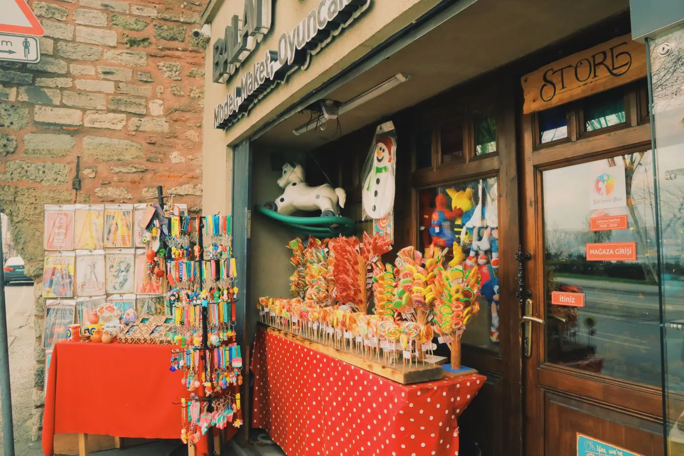 Vivace esposizione di lecca-lecca e giocattoli all'esterno di un negozio di caramelle. Scena di strada urbana. - King Squishy