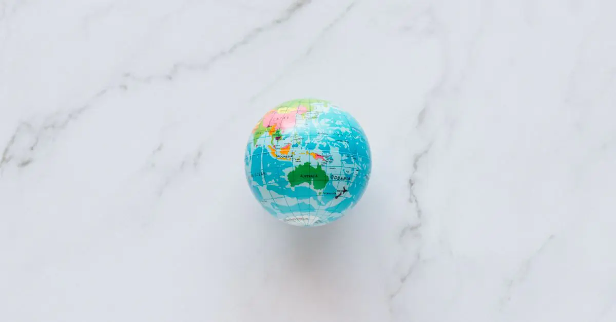 A small, colorful globe rests on a marble surface, symbolizing global exploration and travel planning. - King Squishy