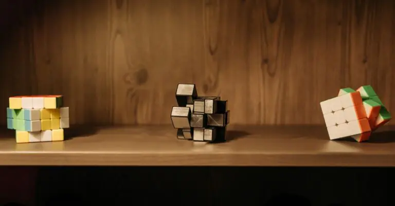 A collection of various Rubik's cubes displayed on a wooden shelf, showcasing unique designs and pat - King Squishy