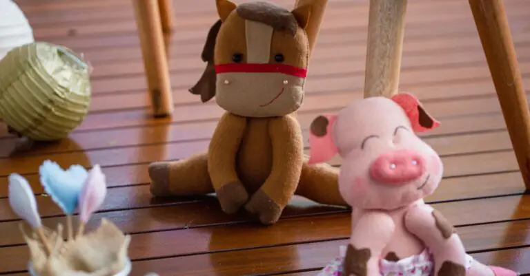 Adorable plush horse and pig toys on a wooden floor, evoking playful childhood memories. - King Squi - King Squishy