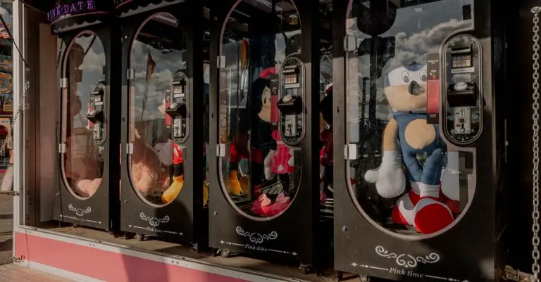 Colorful claw machines filled with plush toys at a fairground arcade, reflecting a fun atmosphe - Ki - King Squishy