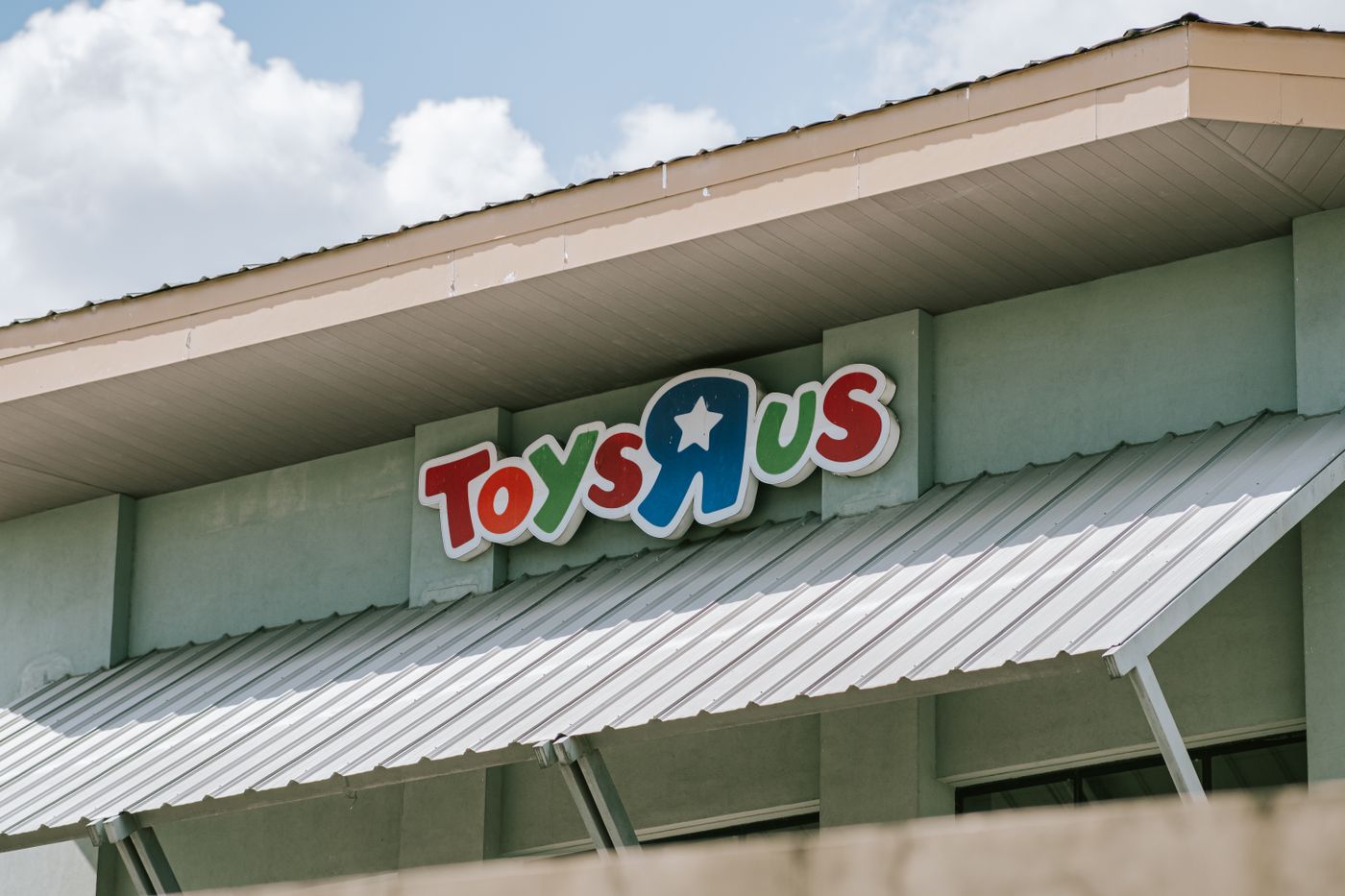سقف ولافتة متجر Toys R Us في يوم مشمس مع سماء زرقاء. - King Squishy