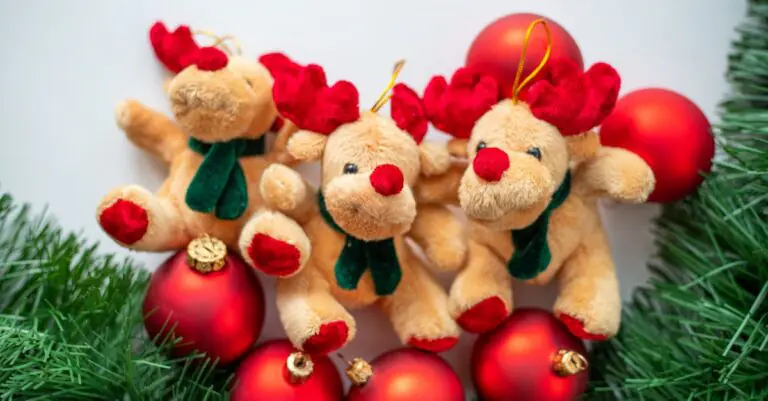 Three adorable reindeer stuffed toys surrounded by red Christmas balls and pine leaves on a whi - Ki - King Squishy