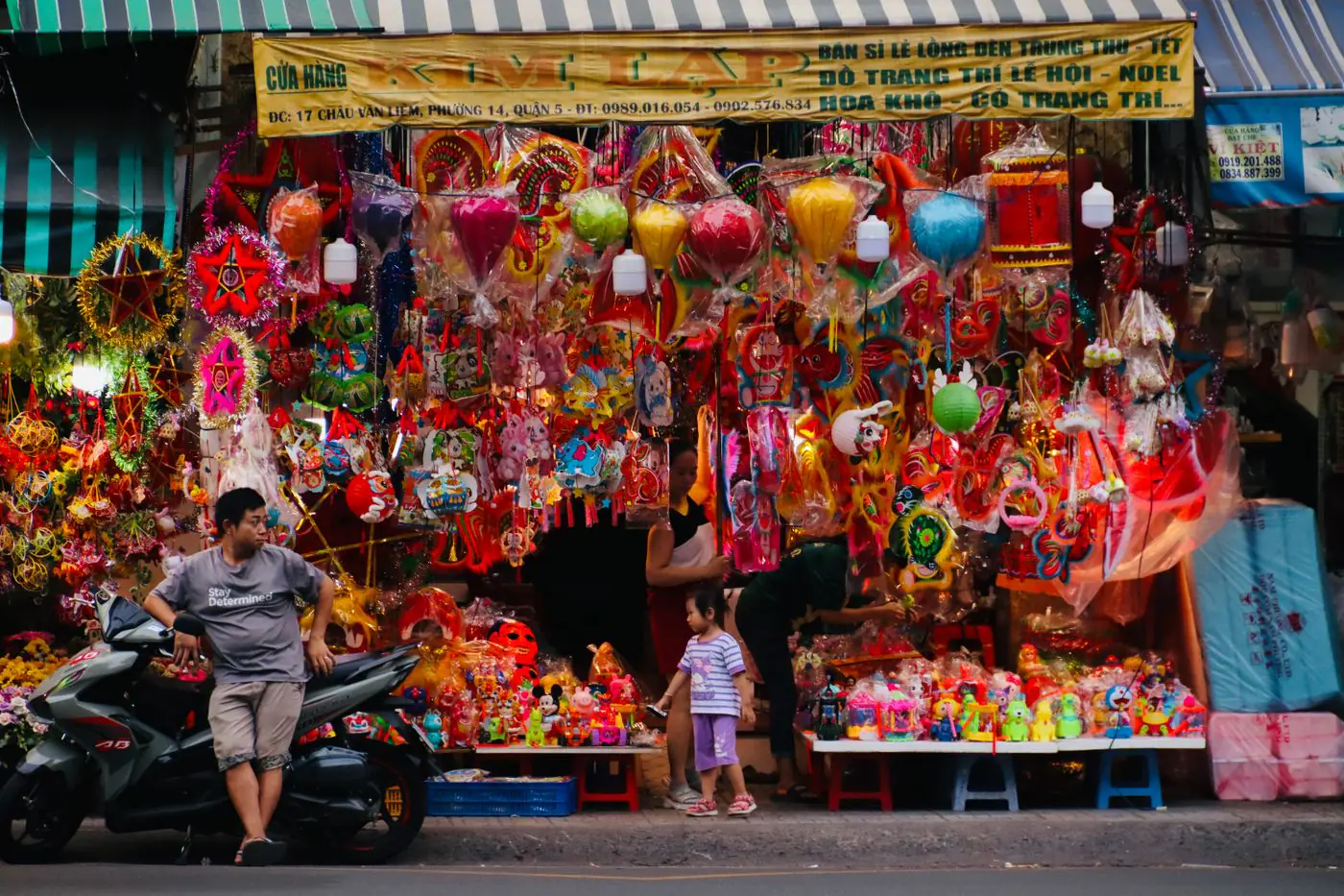 A vibrant display of lanterns and toys outside a busy shop in Vietnam's cityscape. - King Squishy