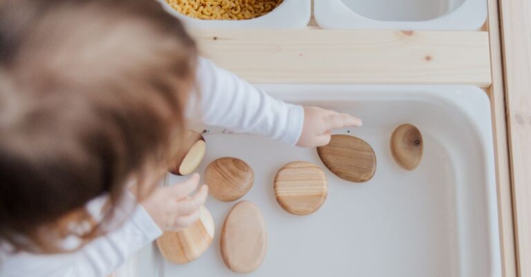 From above of crop faceless child getting beautiful brown stones from white container developing fin - King Squishy