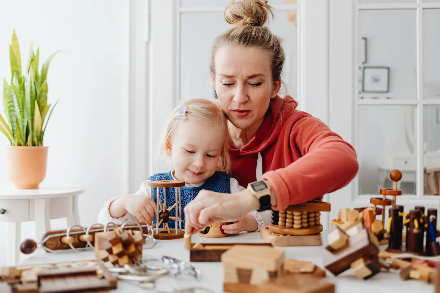 A woman and child enjoy playing and learning with wooden toys indoors.