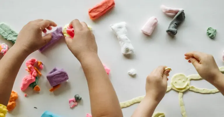 Children engaged in creative clay play, forming shapes and exploring colors on a white table. - King Squishy