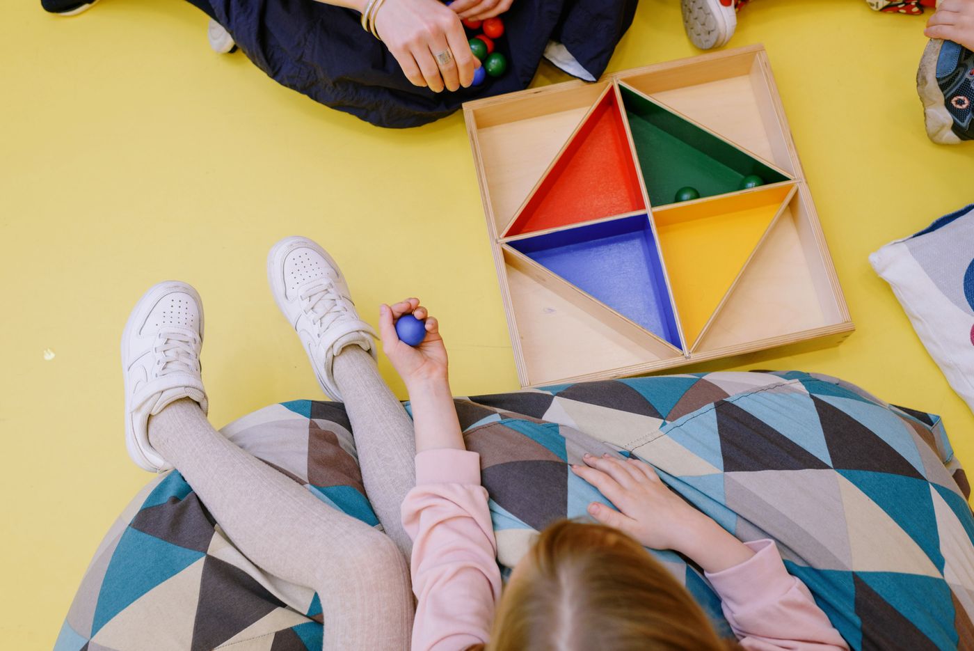 Des enfants jouant avec des jouets en bois colorés dans un intérieur lumineux.