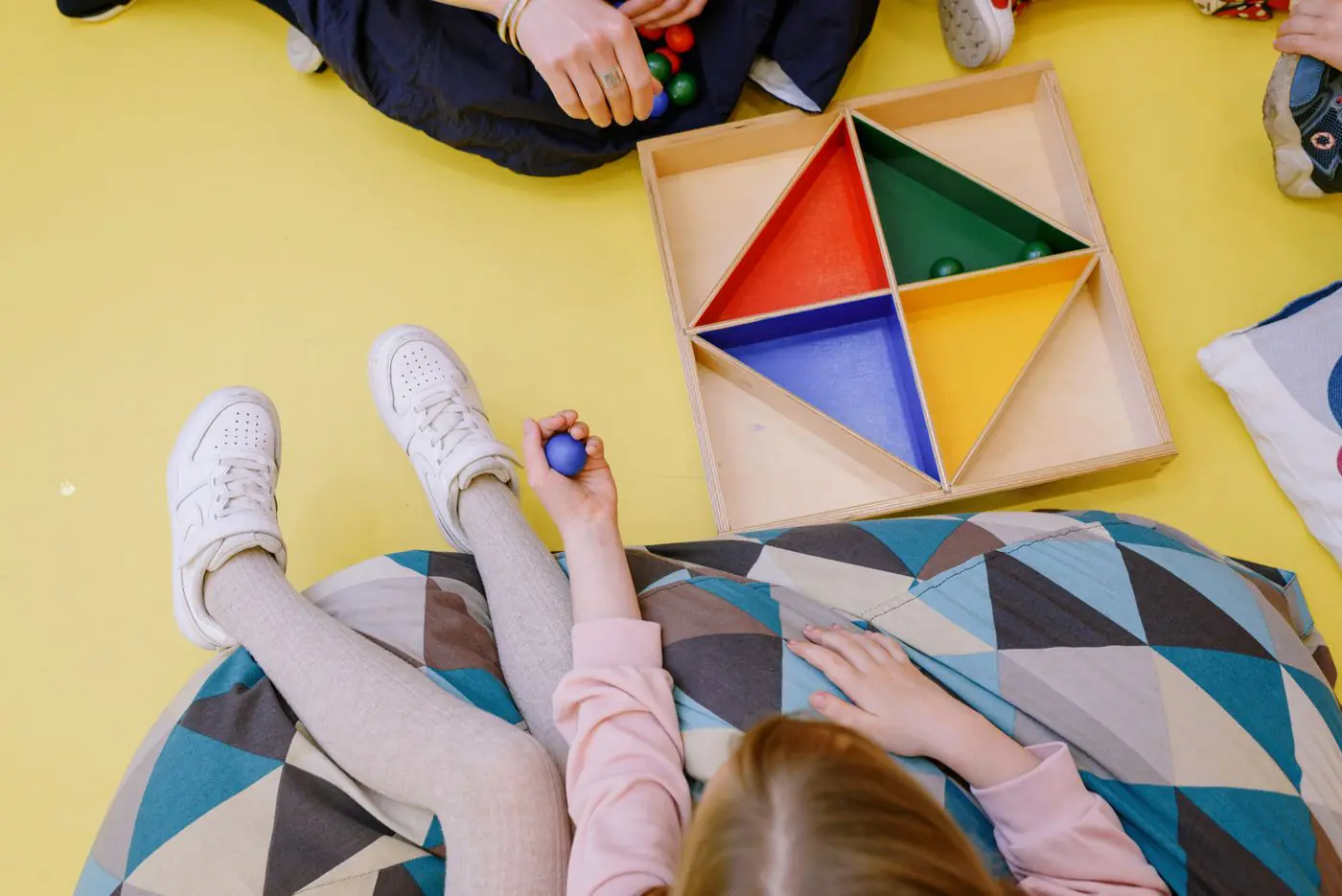 Children engaging in play with colorful wooden toys on a bright indoor setting.