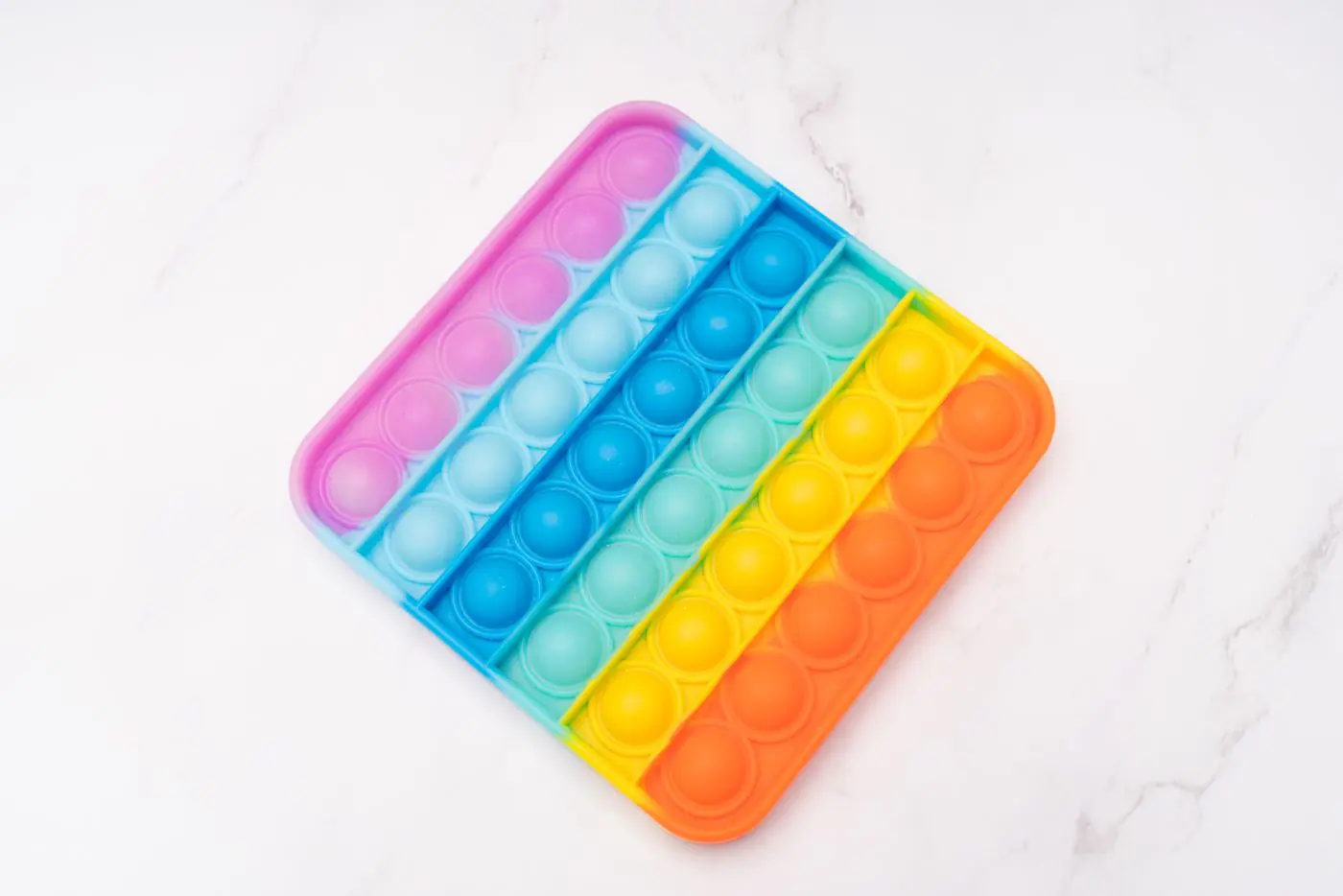 Giocattolo fidget Rainbow Pop It su una superficie bianca luminosa, perfetto per il rilascio dello stress. - King Squishy
