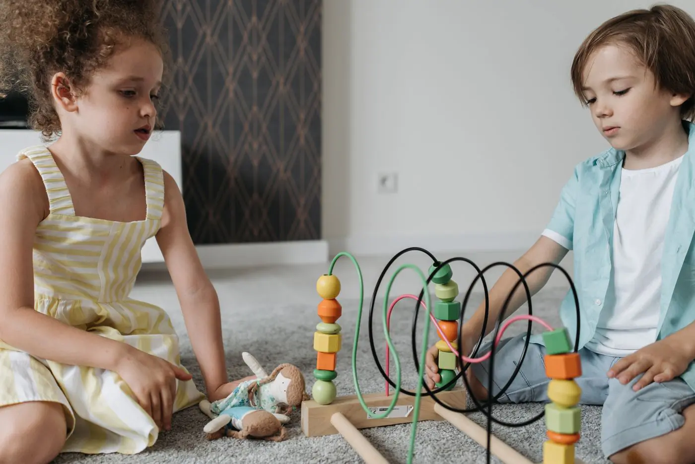 Bambini che giocano con un labirinto di perline colorato sul tappeto, per lo sviluppo delle capacità cognitive. - King Squishy