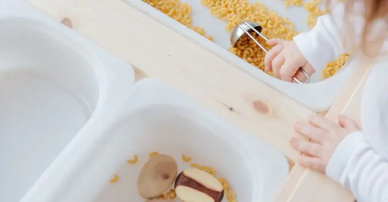 From above view of anonymous little kid taking raw pasta with metal spoon from white plastic contain - King Squishy