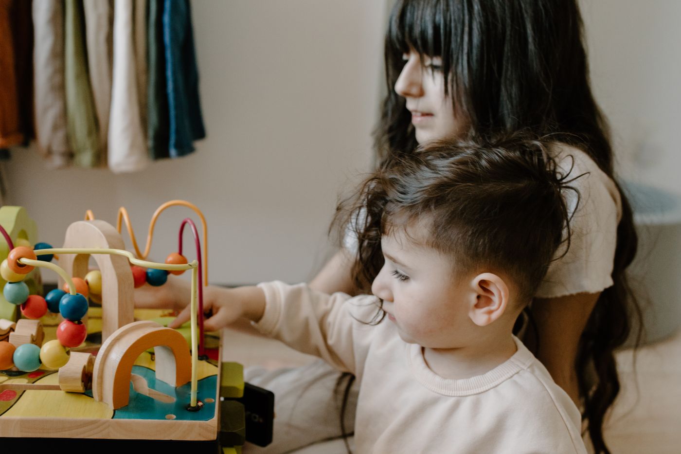 Zwei Kinder beschäftigen sich an einem Tisch mit Holzspielzeug und fördern Fantasie und Spielzeit.