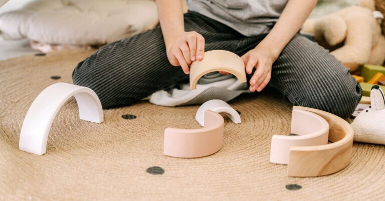 A child engaging in play with wooden arched blocks, enhancing motor skills and creativity. - King Squishy