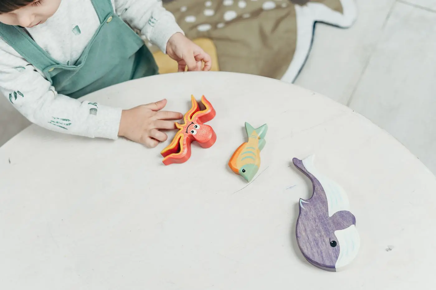 A child engaged with colorful wooden sea animal toys, fostering creativity and fun.