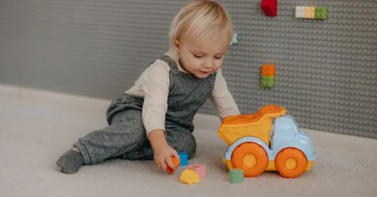 Cute toddler engaged with colorful blocks and toy truck indoors. - King Squishy