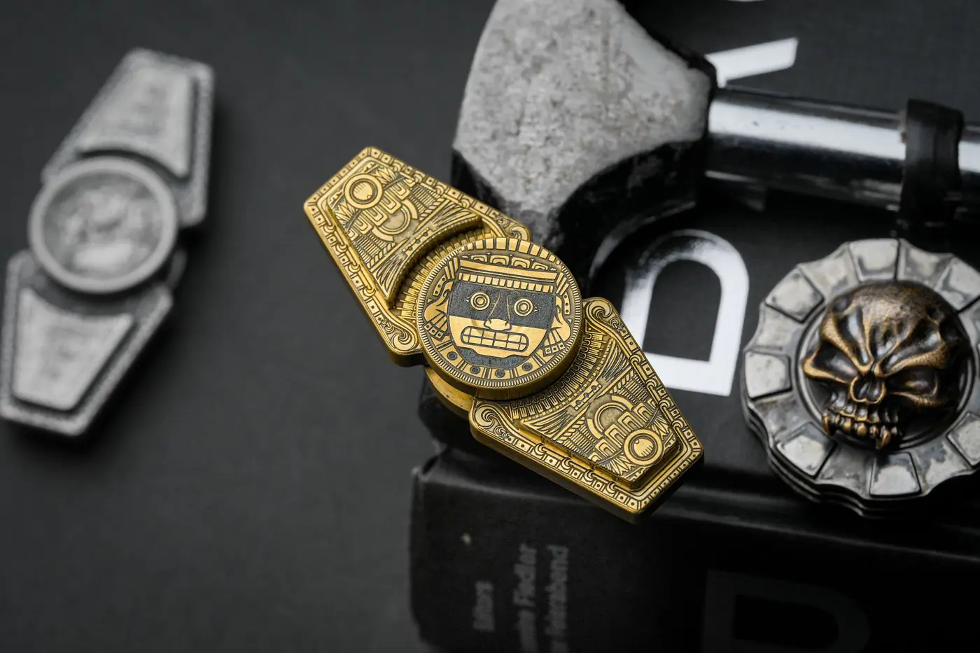 Metaliczny fidget toy w tematyce azteckiej z misternymi detalami na ciemnym tle, idealny dla miłośników kultury i osób szukających odprężenia. - King Squishy