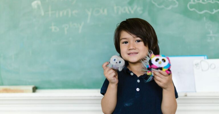 Smiling child holds plush toys in a classroom setting, with chalkboard background. - King Squishy