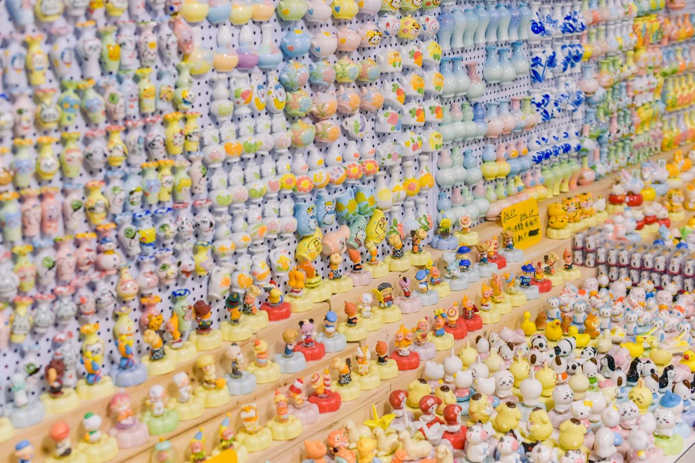 Kolorowa kolekcja ceramicznych figurek, starannie ułożonych na półkach wystawowych, prezentująca różnorodne wzory ręcznej roboty. - King Squishy