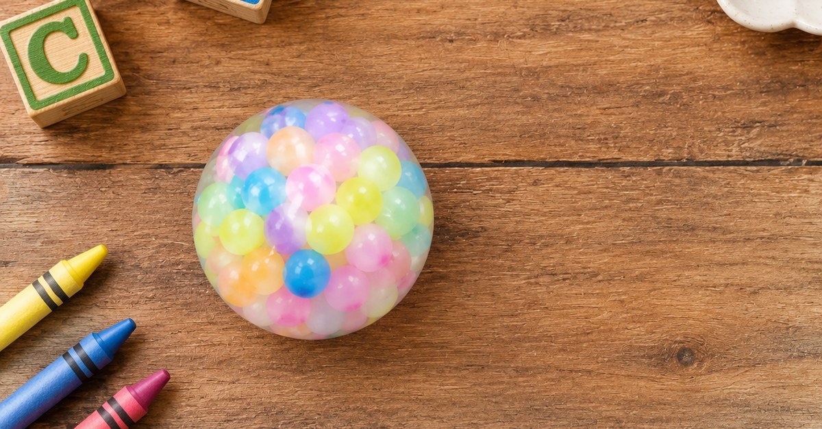Vue en plongée d'une bille sensorielle colorée avec des cubes d'alphabet et des crayons, destinée aux acheteurs de crèche - King Squishy